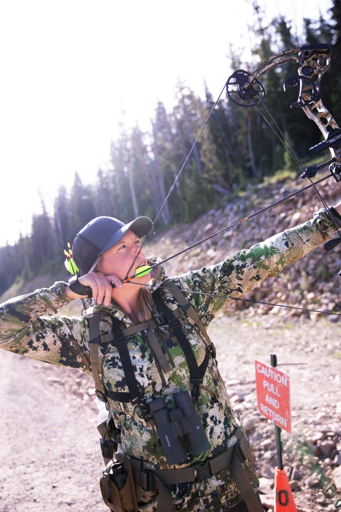 woman draws compound bow