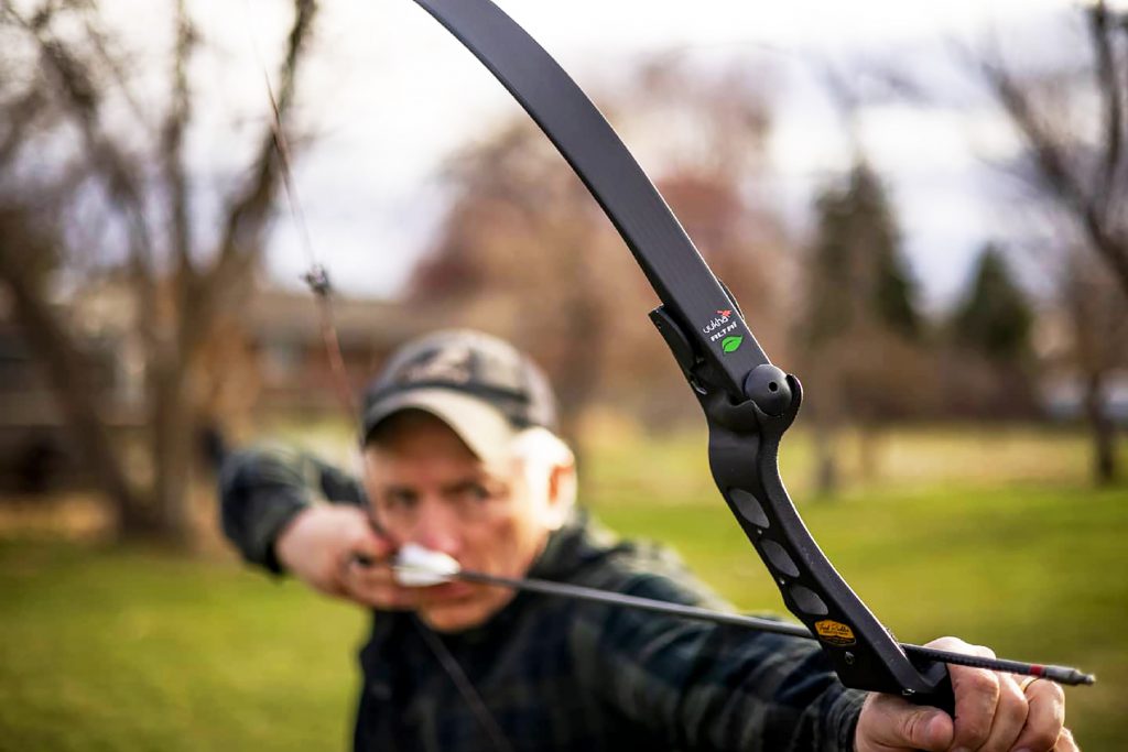 man firing a tradional bow