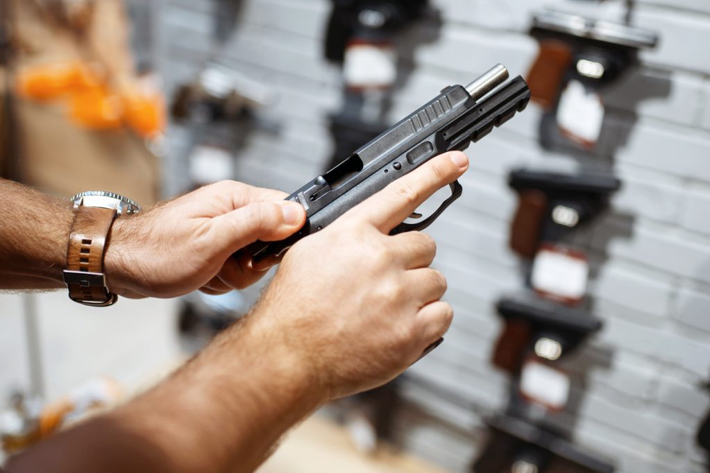man examining handgun at gun counter