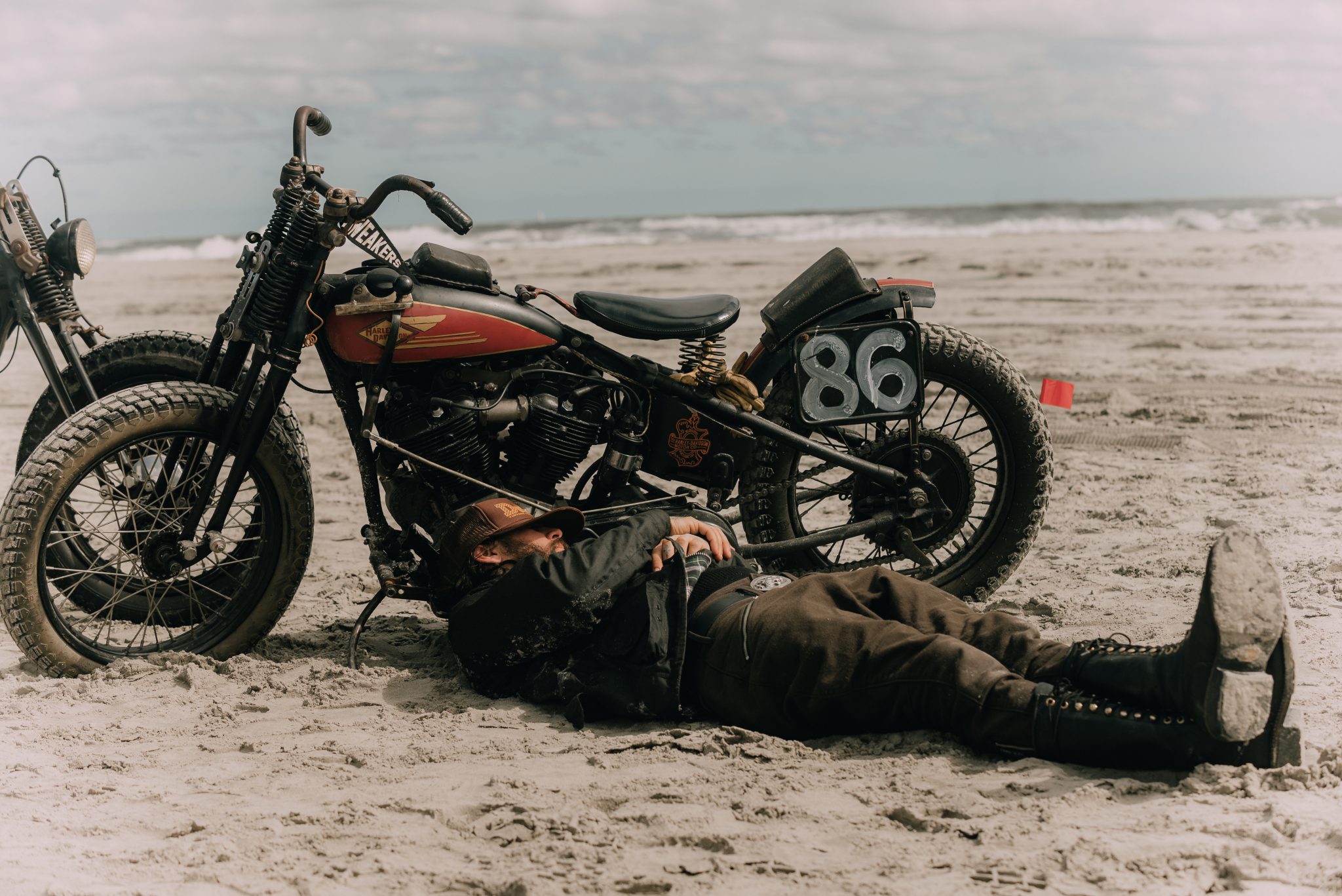 man sleeping near motorcycle on beach
