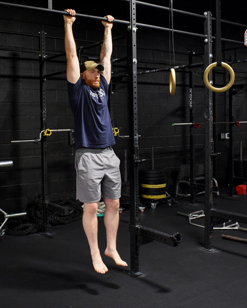 man performing a dead hang to improve your pullups