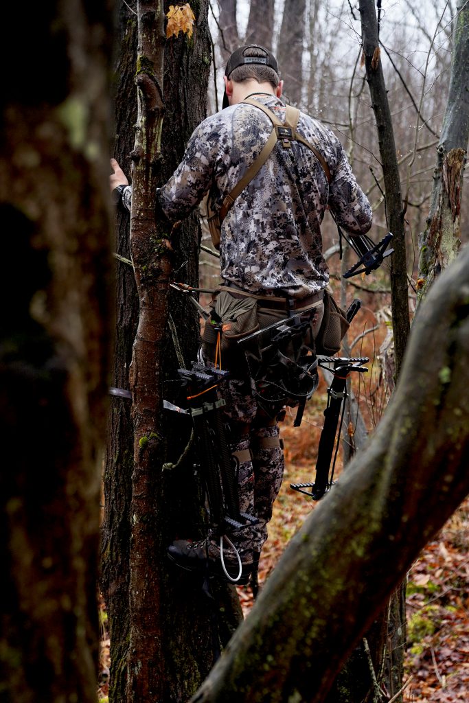 man in climbing deer stand while learning how to hunt public land