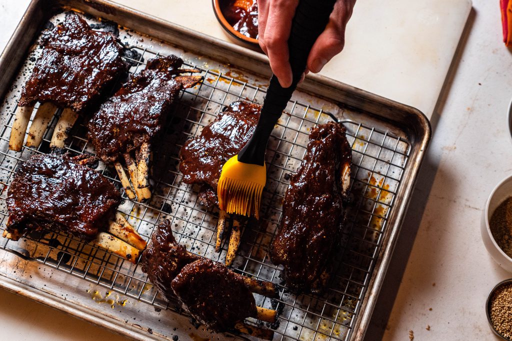 brushing bbq sauce on meat