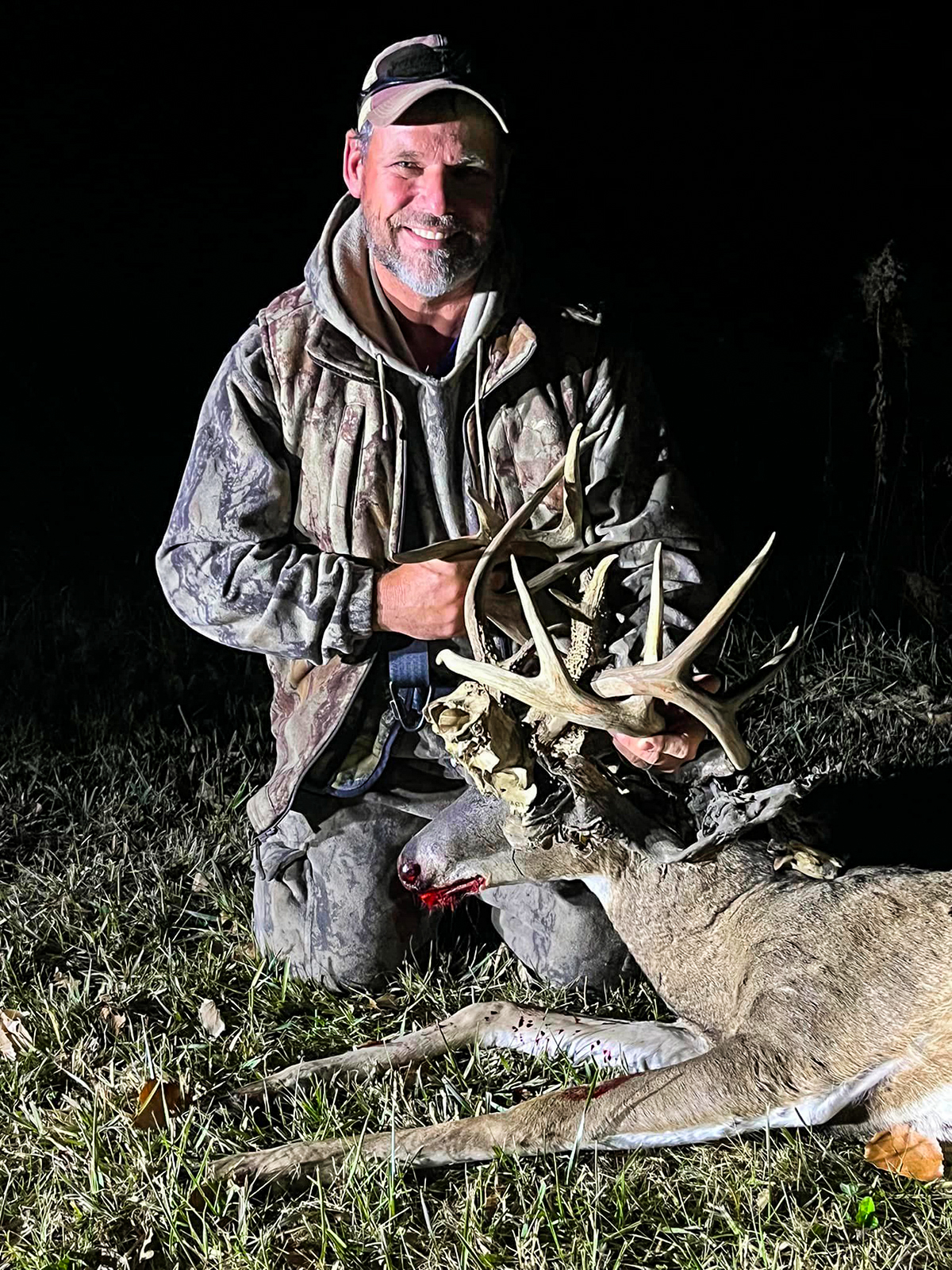 Hunter posing with his buck with another deer skull