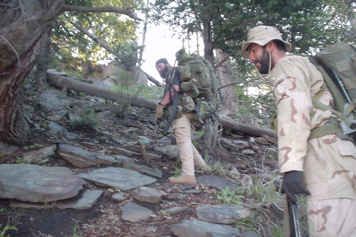 In spring 2004, Tyr Symank, left, and an interpreter ascend a steep slope during a multiday patrol in the Hindu Kush mountains.