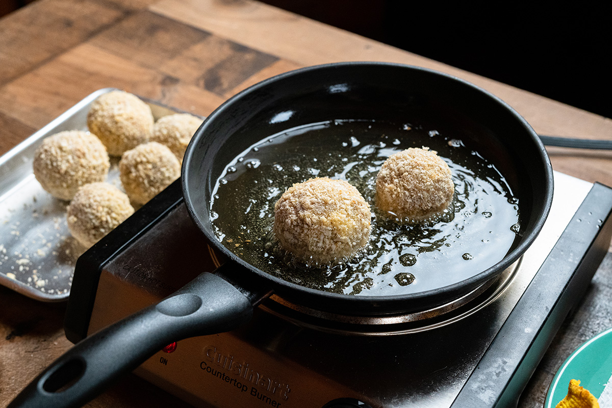 Fry the boudin balls on all sides at low heat so that the inside warms without over-darkening the outer breading.