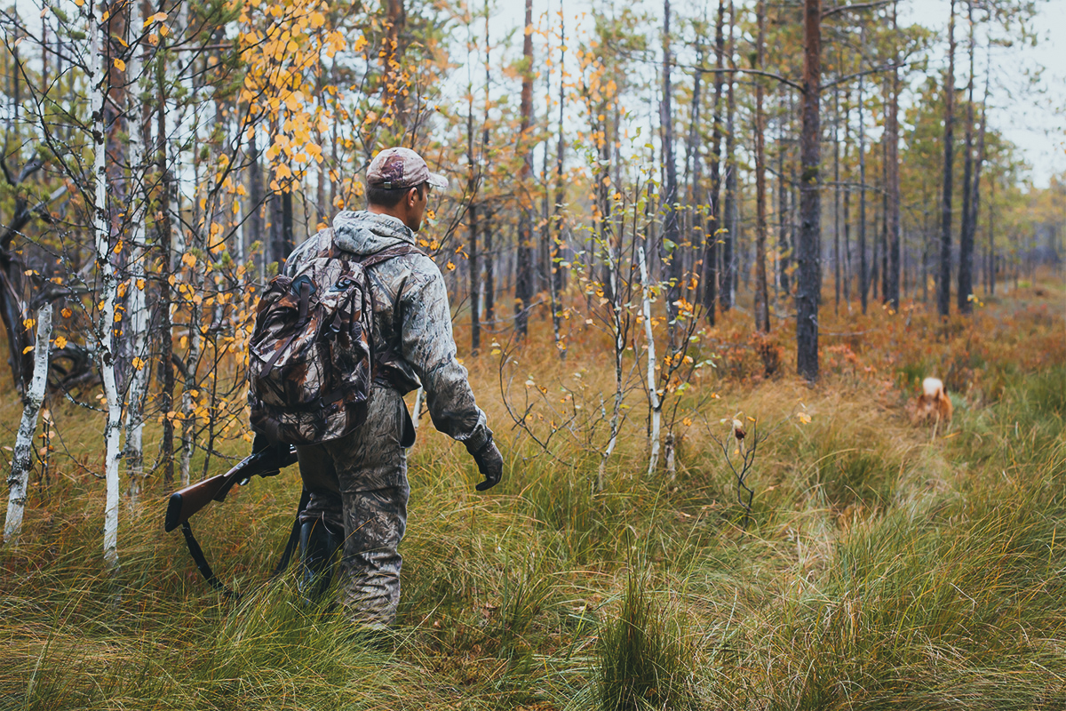 Hunter walking through the woods wearing a hunting backpack