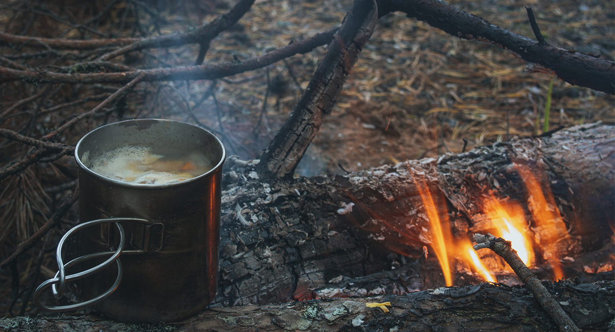 Cooking hiking food on a campfire in a metal mug