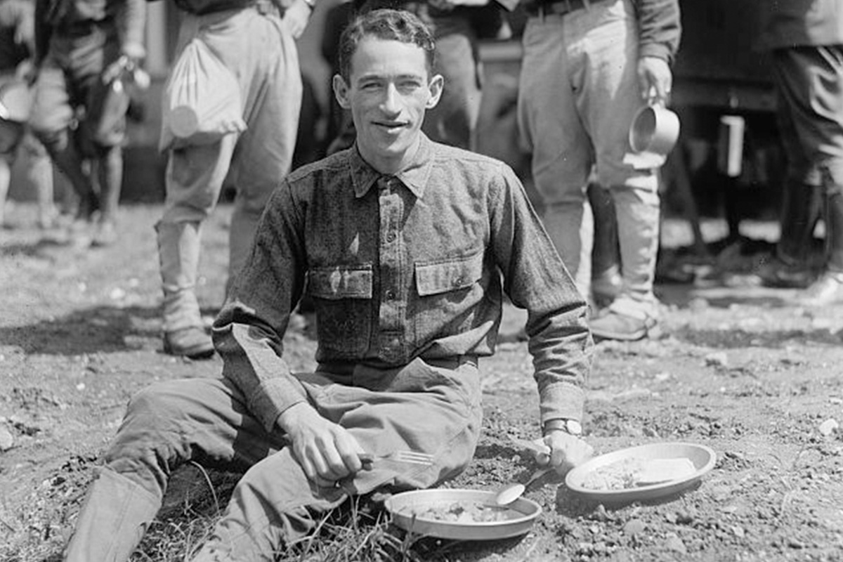 A soldier eats from his mess kit circa 1918.