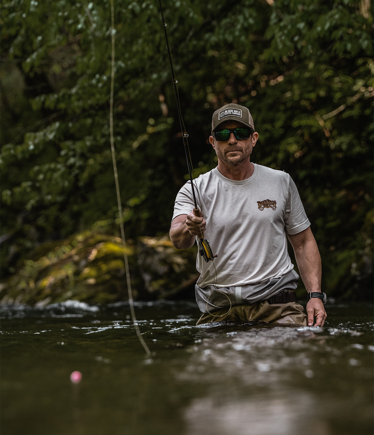 Man wearing a cowboy hat while fly fishing in a river in the